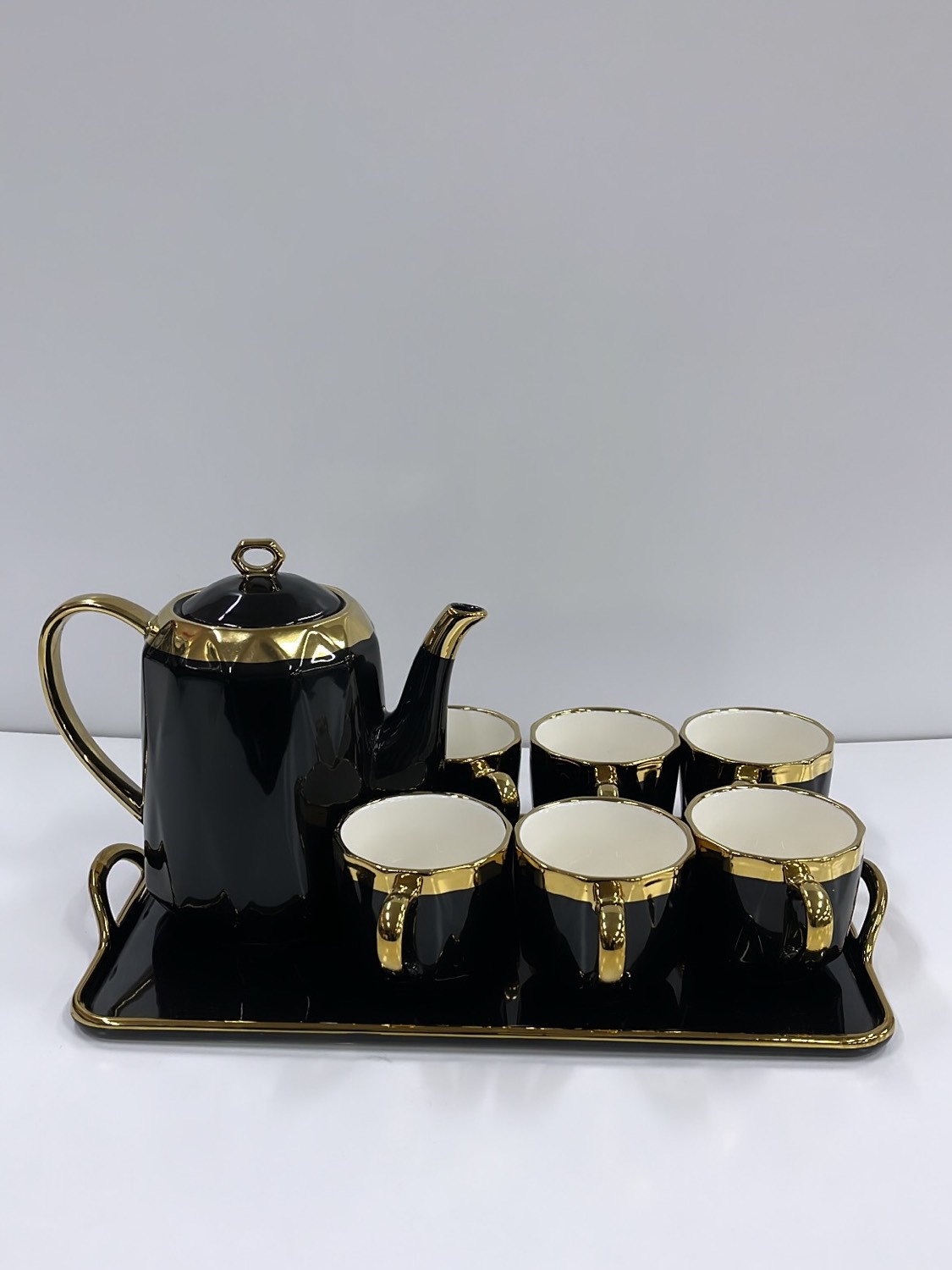 Black and gold ceramic tea set with matching jug