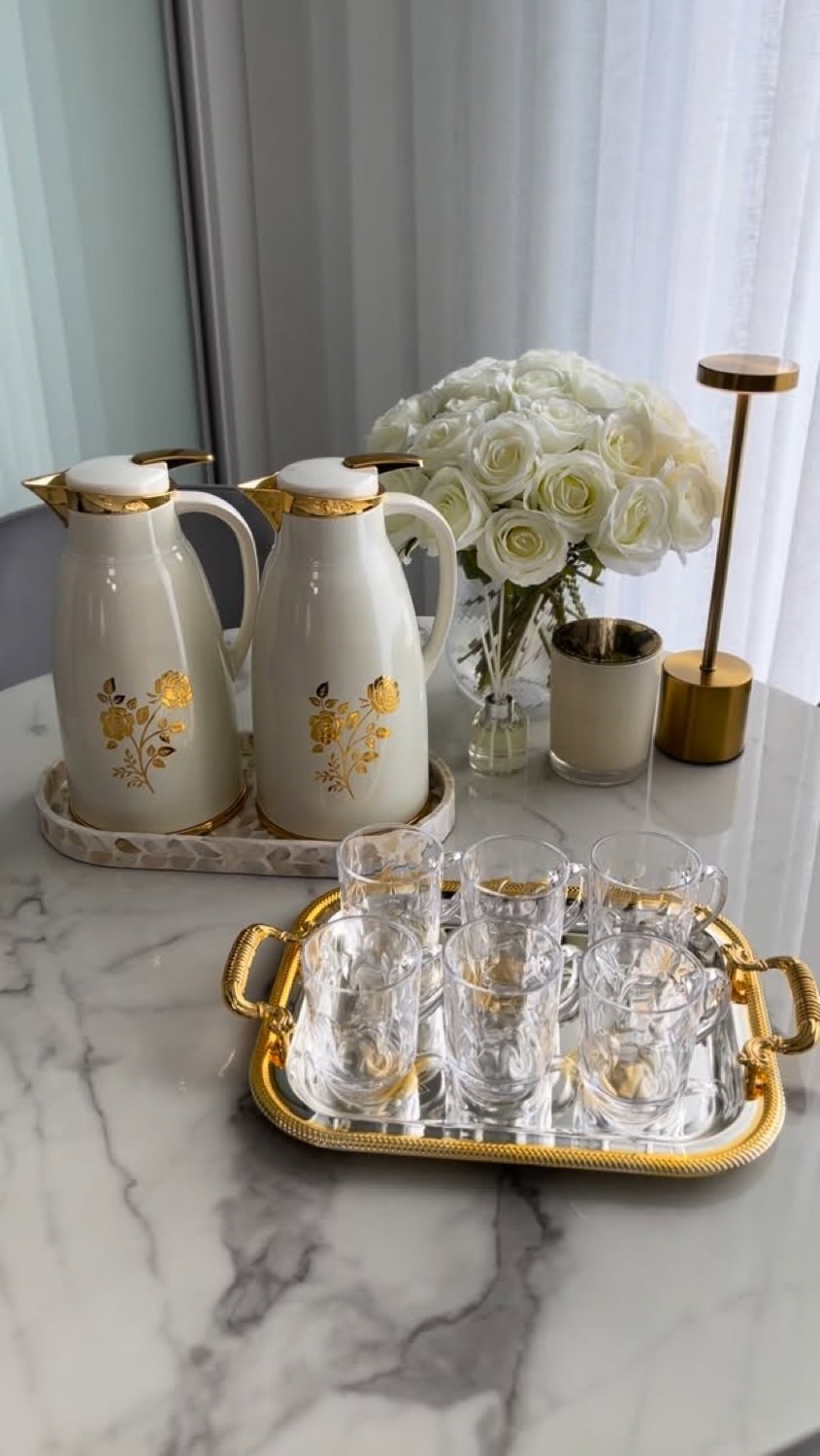 White and gold tea flasks with glass cups on a tray